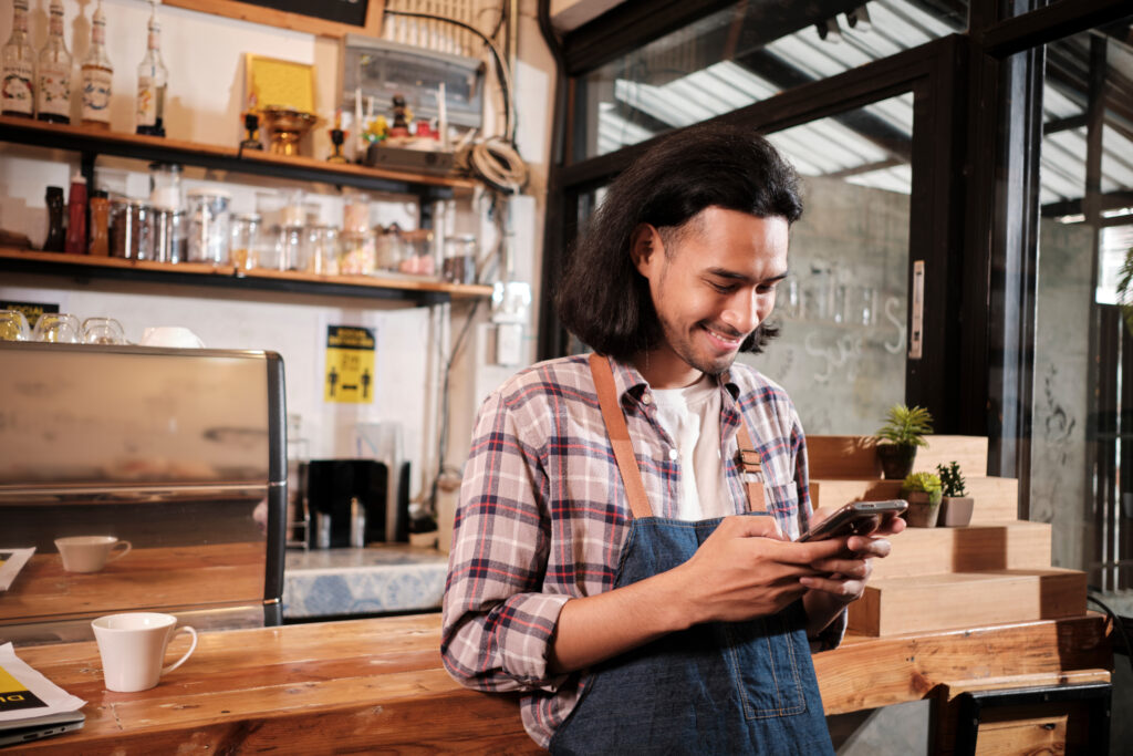 An individual in a coffee shop on their mobile device using Textify's text messaging platform.