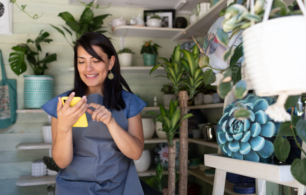 An individual in a plant shop on their mobile device, accessing Textify's SMS marketing platform.