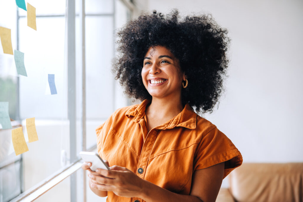 An individual is smiling while holding their mobile device.